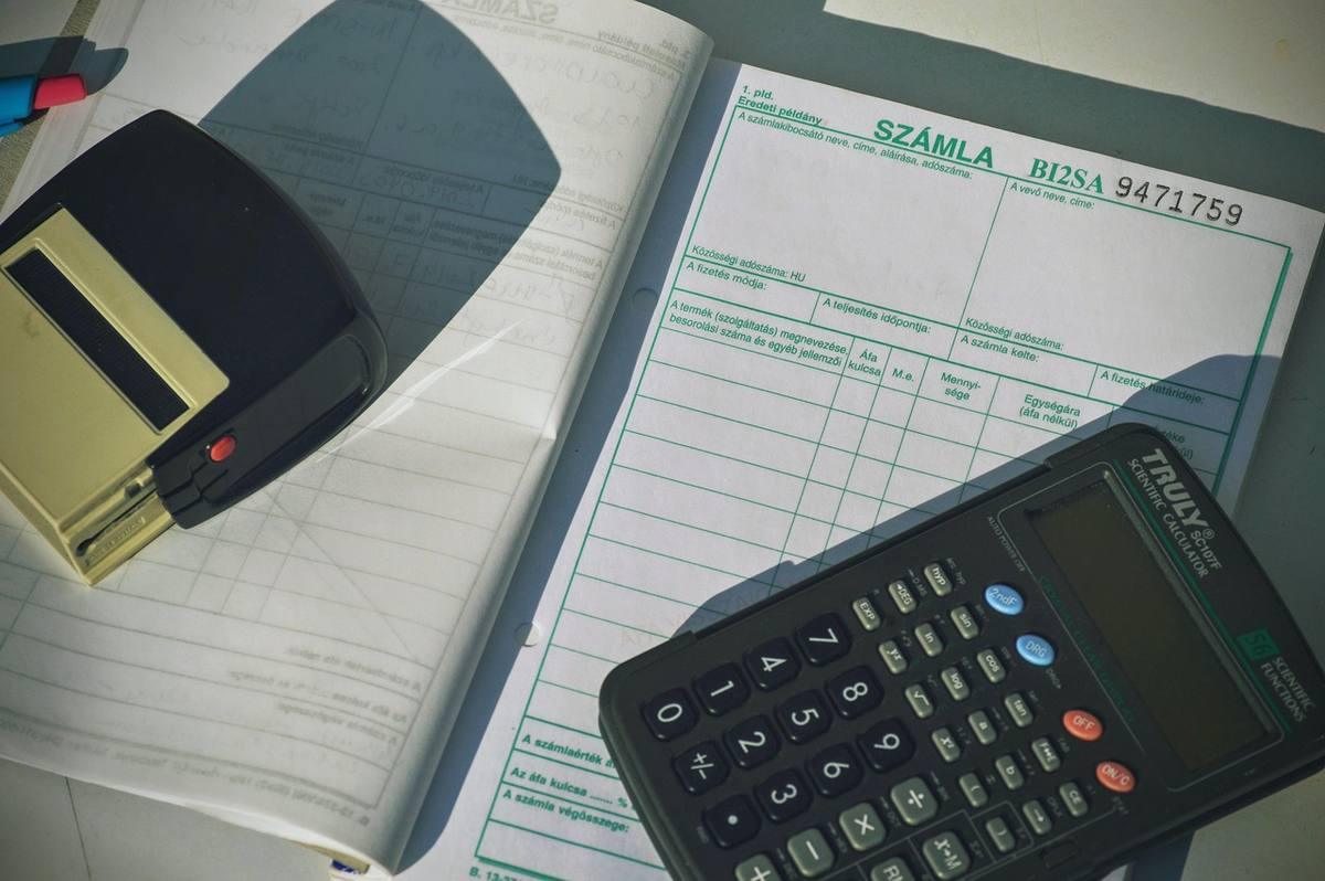 Calculatrice, facture et tampons sur un bureau avec carnet de notes comptables