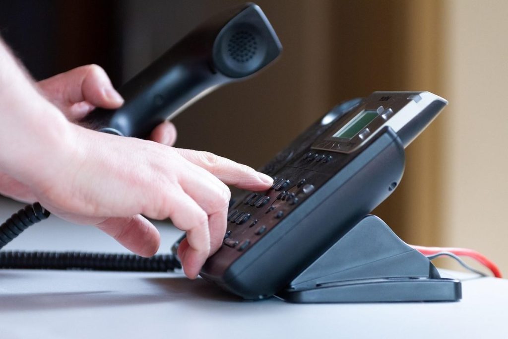 Opérateur tenant un combiné téléphonique avec casque audio pour un appel professionnel