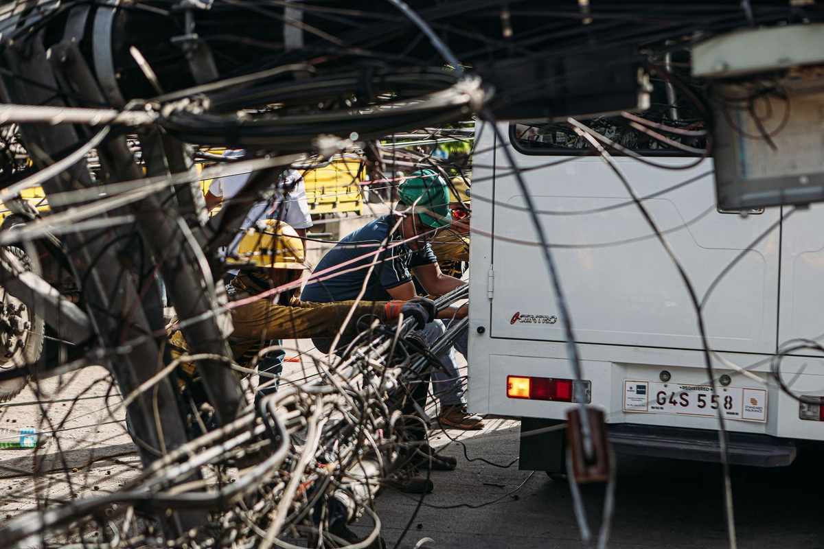 Ouvriers manipulant des câbles électriques près d'un camion blanc dans une ville