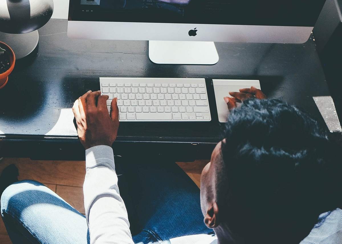 Une personne travaille sur un ordinateur iMac à un bureau Une personne travaille sur un ordinateur iMac à un bureau